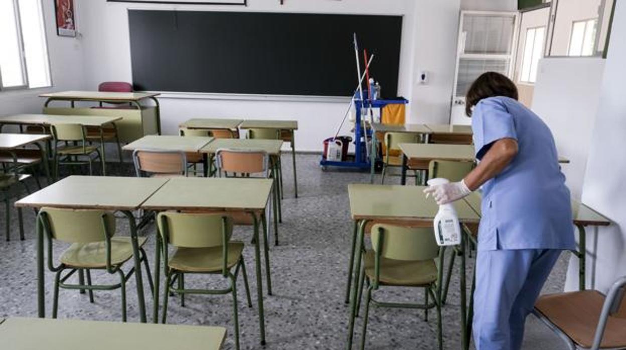 Una limpiadora desinfecta una clase en un colegio de Cádiz.