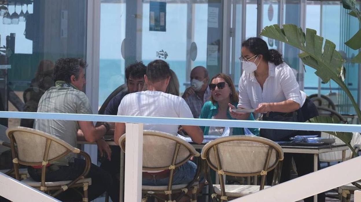 Una camarera con mascarilla atiende a los clientes en una terraza de Cádiz.