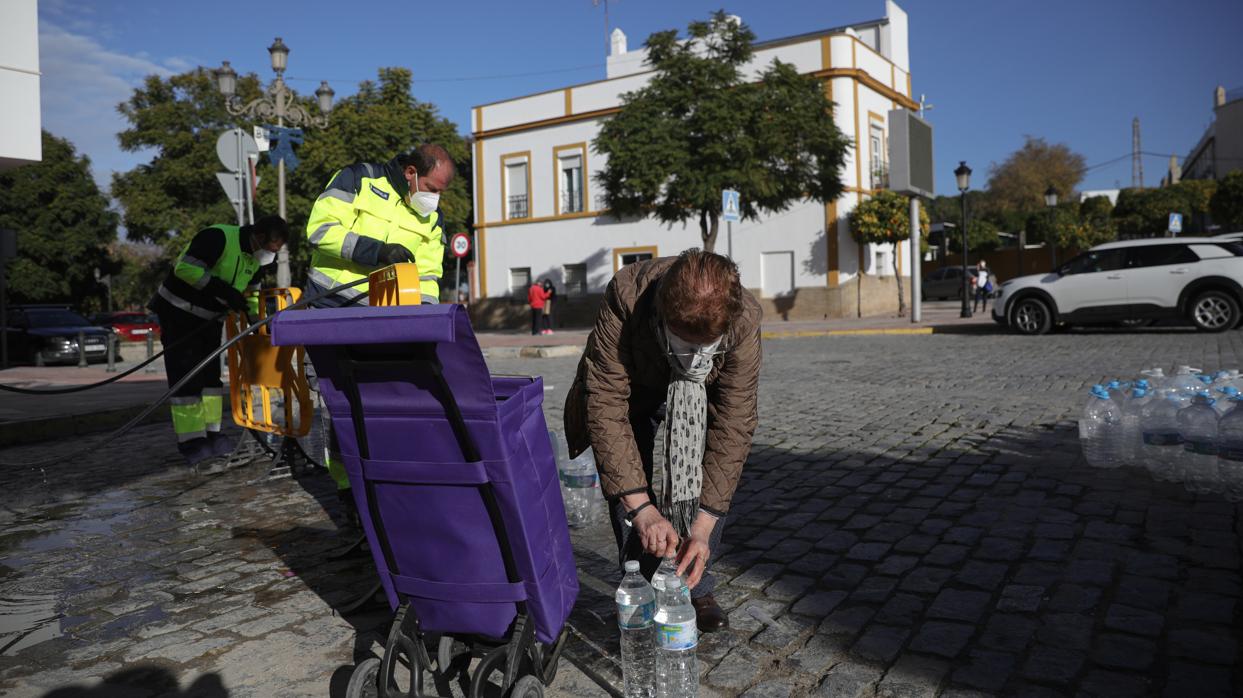 Una vecina de Marchena recoge varias botellas de agua del camión cisterna