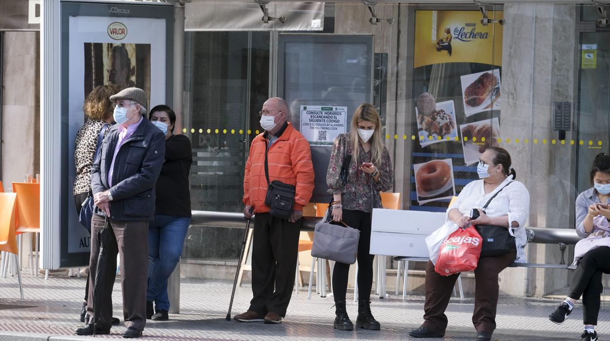 Varias personas esperan al autobús con mascarilla durante este otoño del coronavirus en Cádiz.