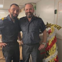 Dos miembros de la dotación de la fragata junto a un árbol de Navidad.