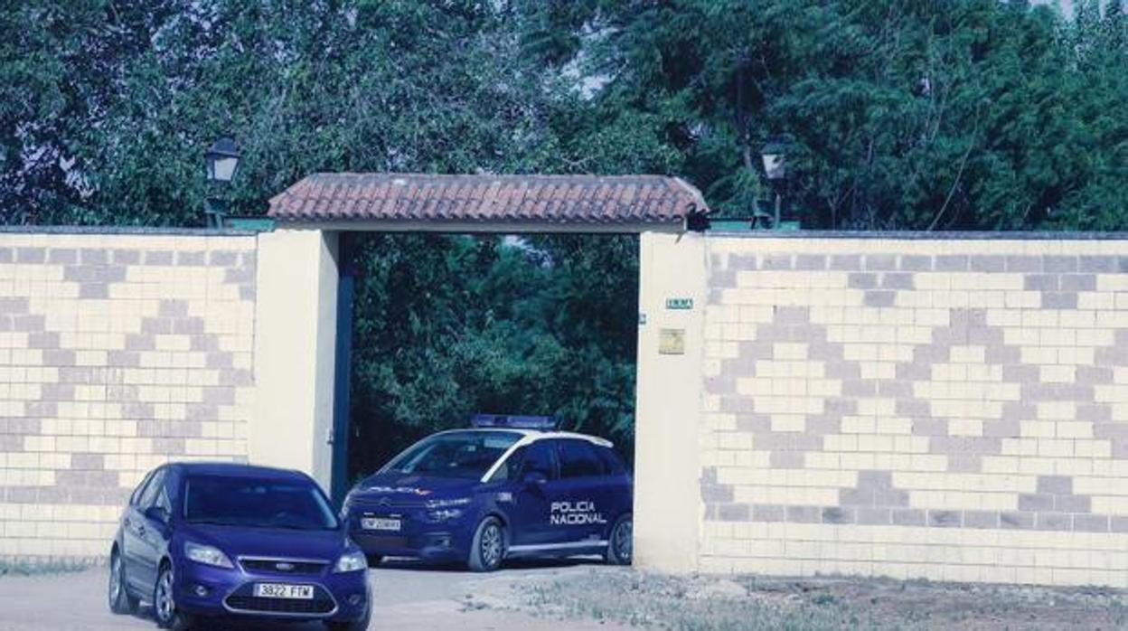 Dos coches de la Policía Nacional abandonan la finca donde ocurrieron los hechos el pasado verano