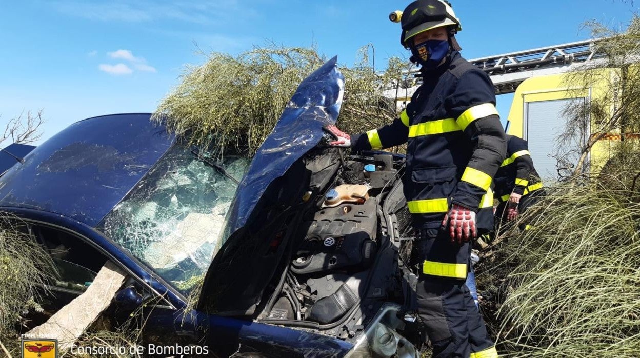 Uno de los bomberos, jnuto al coche siniestrado.