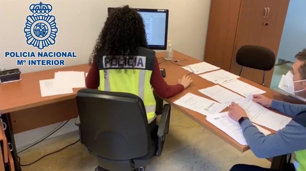 Una agente de la Policía inspeccionando documentación en un ordenador.