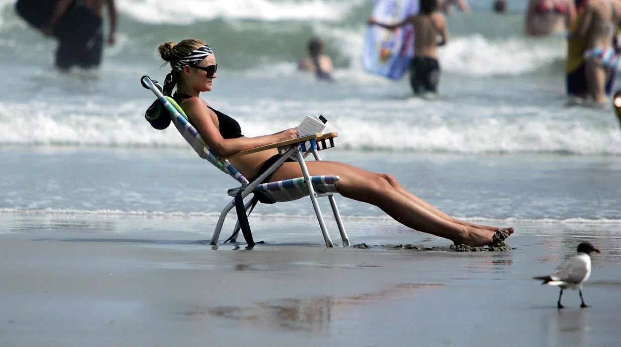Imagen de archivo de una joven leyendo en la playa.