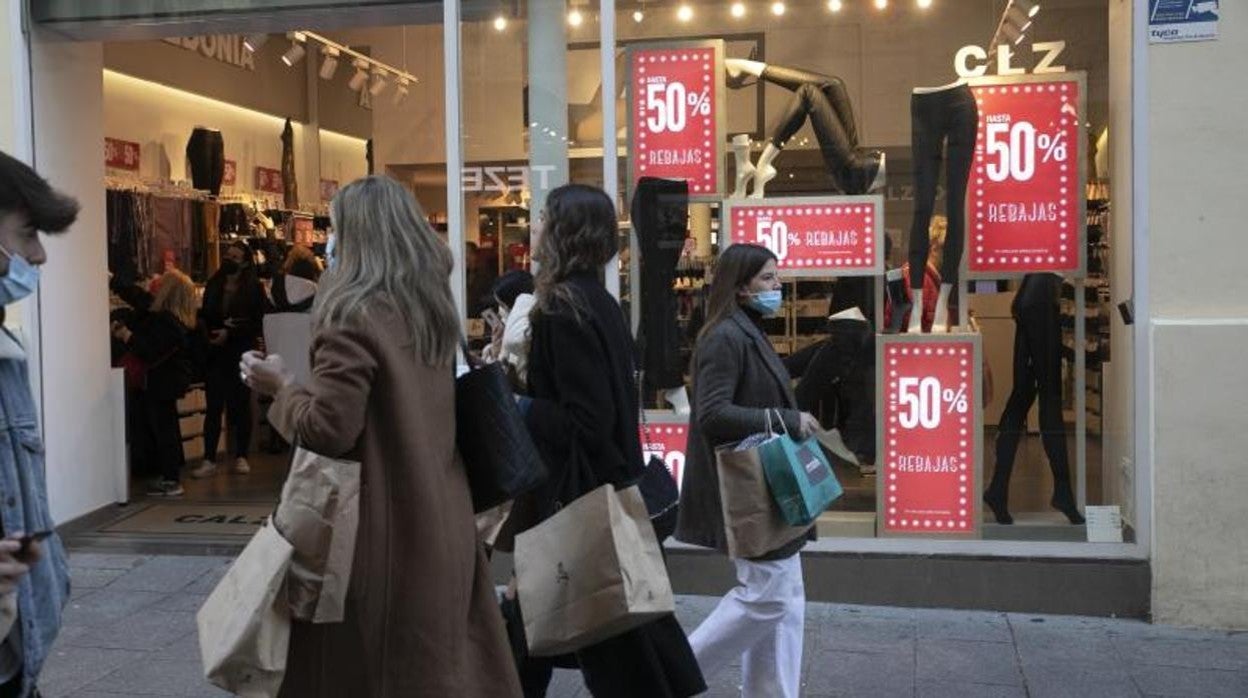 Varias personas pasan por delante de un comercio en rebajas