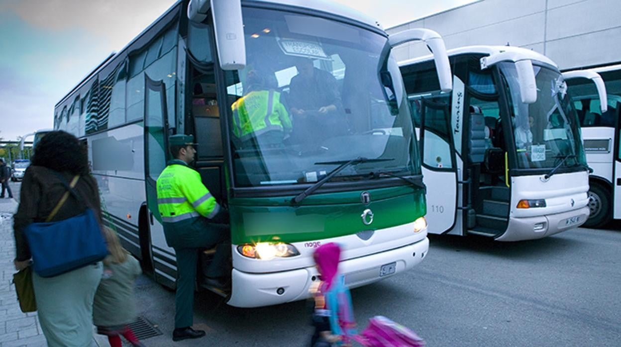 Un agente de la Guardia Civil inspecciona un autobús de transporte escolar