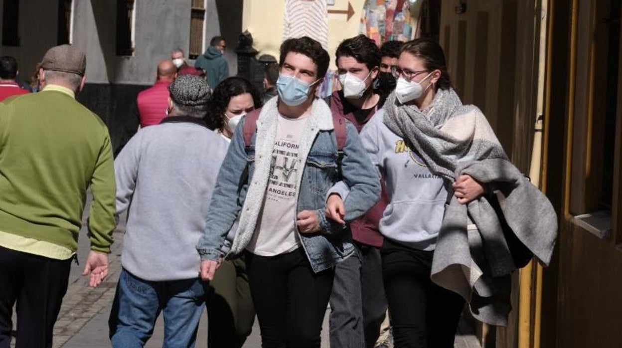 Jóvenes gaditanos pasean con mascarilla por las calles de la capital.