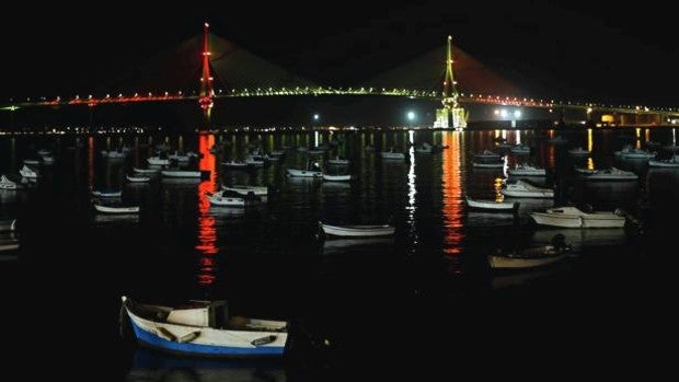 El puente de la Constitución se ilumina con la bandera nacional para despedir al Juan Sebastián de Elcano