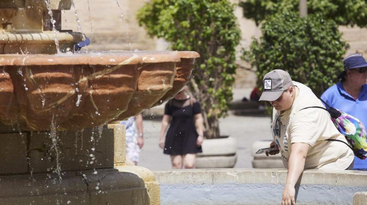 Un turista se refresca en una fuente de Sevilla