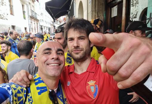 Martín no dudó en mezclarse con la afición gaditana en la puerta de su bar. En la foto, con el gaditano David Mera, otro fijo en los desplazamientos cumbres.