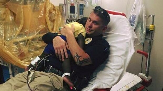 La emotiva fotografía de un bebé perdido consolado por un policía que causa sensación en Facebook