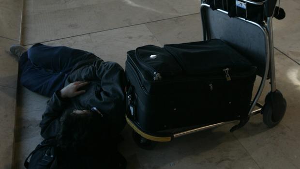 Un viajero duerme en el aeropuerto de Madrid - Barajas