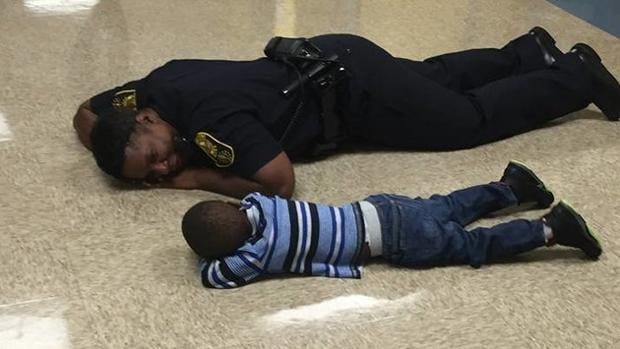 Momento en el que la policía se tumba junto al niño en el suelo del colegio