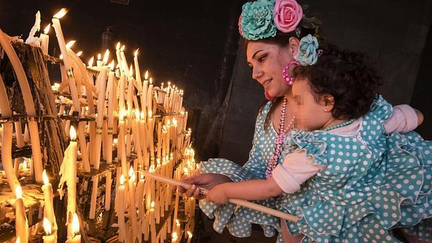 Una rociera coloca unas velas a la Virgen del Rocío