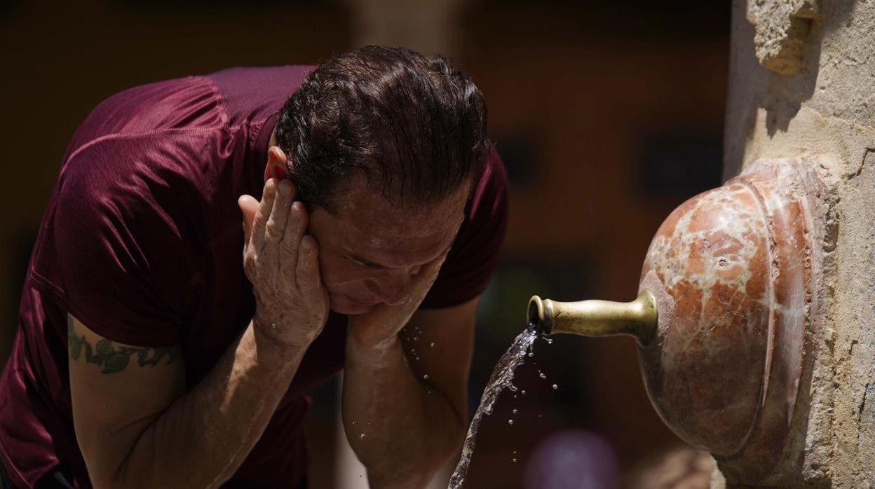 Un hombre se refresca en una fuente por el calor extremo