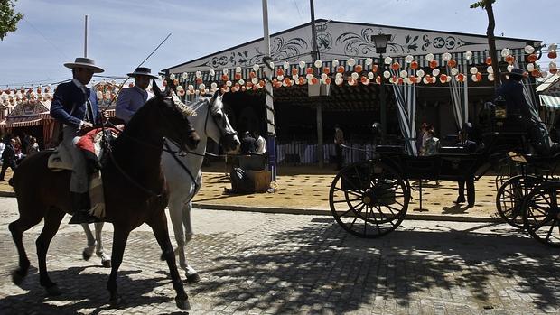 Dos caballistas pasean por una calle del real