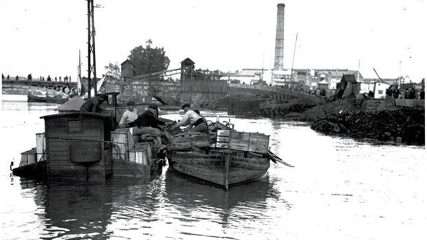 Operarios traspasando enseres entre dos embarcaciones en medio del río