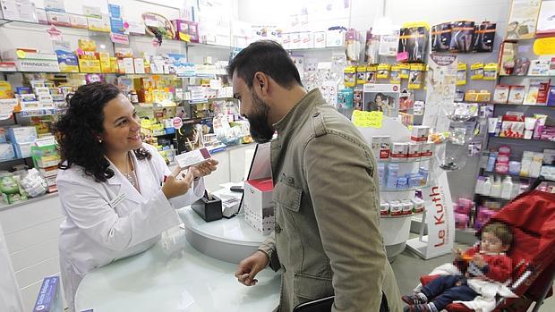 Una farmacéutica muestra la caja de la vacuna a un cliente