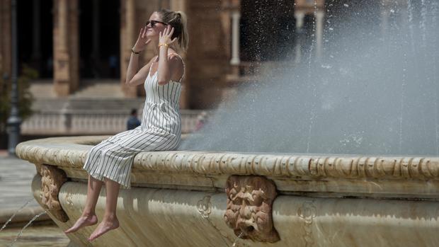 Una joven se refresca en la fuente de la PLaza de España