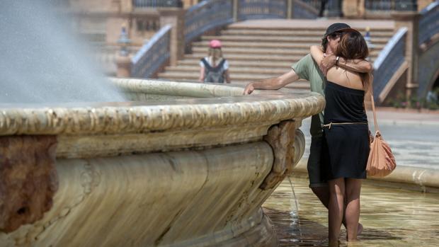 Una pareja se refresca en la fuente de la plaza de España