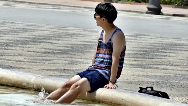 Un joven se refresca del calor en una fuente