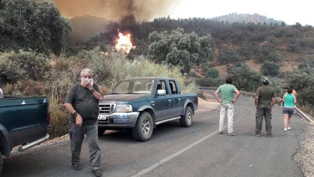 Lugareños con sus vehículos observan el incendio