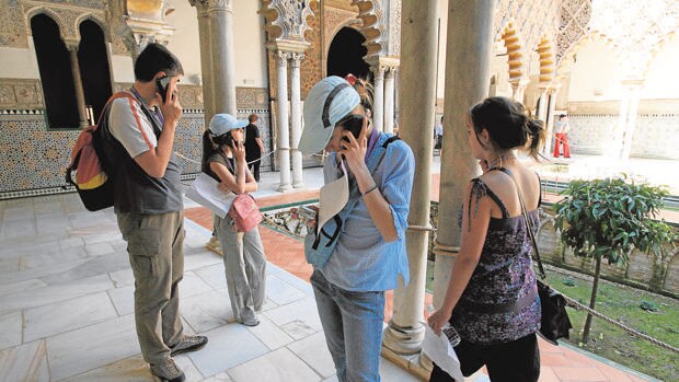 Varios turistas pasean por el Alcázar siguiendo las indicaciones de las audioguías