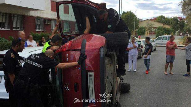 La Policía tratando de asistir al conductor del vehículo volcado