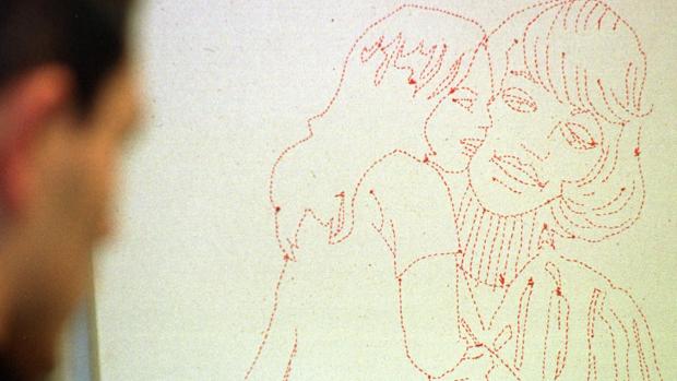 Un hombre mira un grabado de una mujer y una niña en una exposición en Sevilla