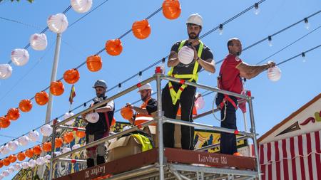 Operarios colocando farolillos en el real de la Feria de Abril de Sevilla