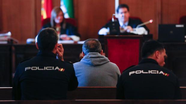 El acusado, escoltado por la Policía en el banquillo de la sala donde está siendo juzgado