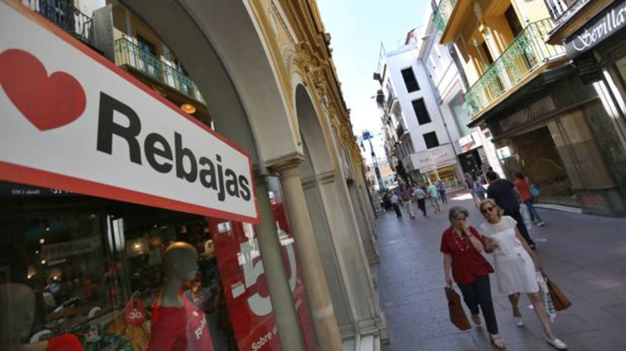 Dos clientas pasean ante uno de los comercios del Centro de Sevilla