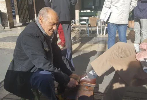 Juan Martín, limpiando los zapatos de un cliente en plaza de Cuba