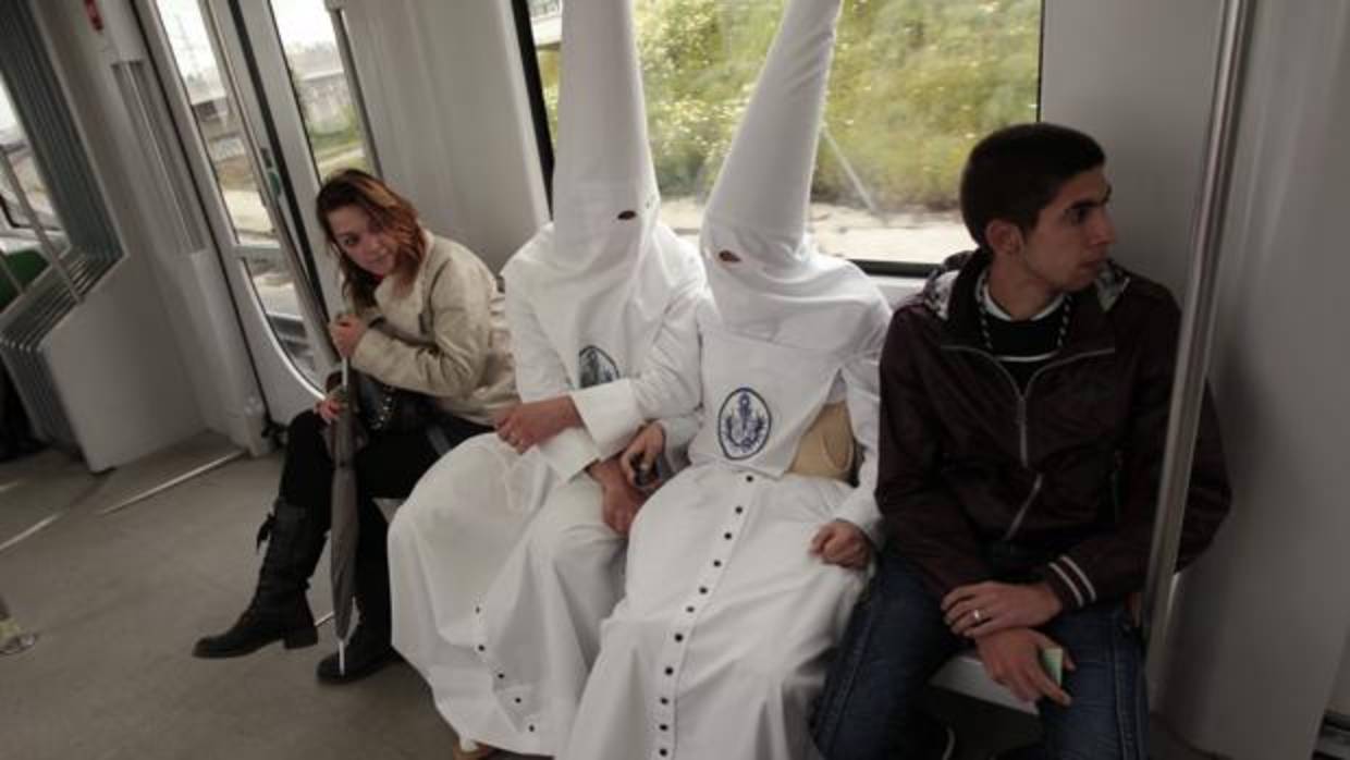 Dos nazarenos de La Candelaria, entre otros usuarios del Metro de Sevilla