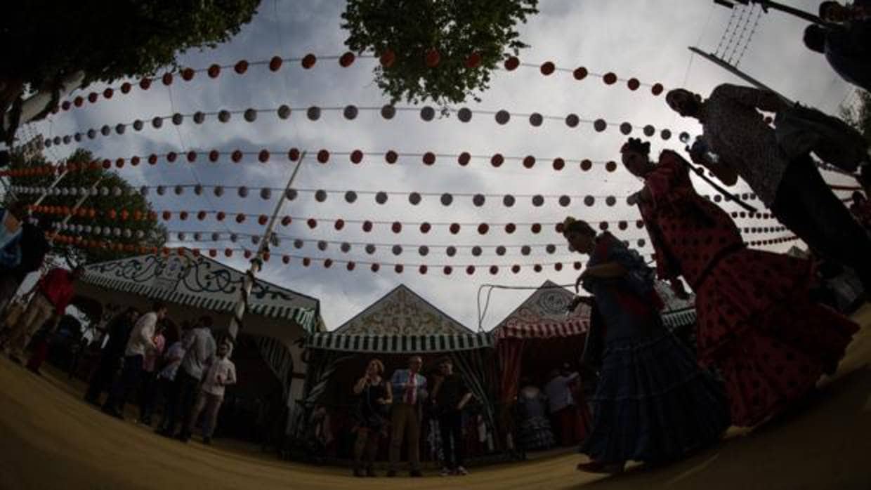 Flamencas pasando bajo un cielo de farolillos en la Feria este viernes