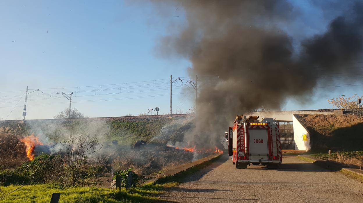 Un cambión y efectivos de bomberos actuando en la zona donde han ardido los neumáticos