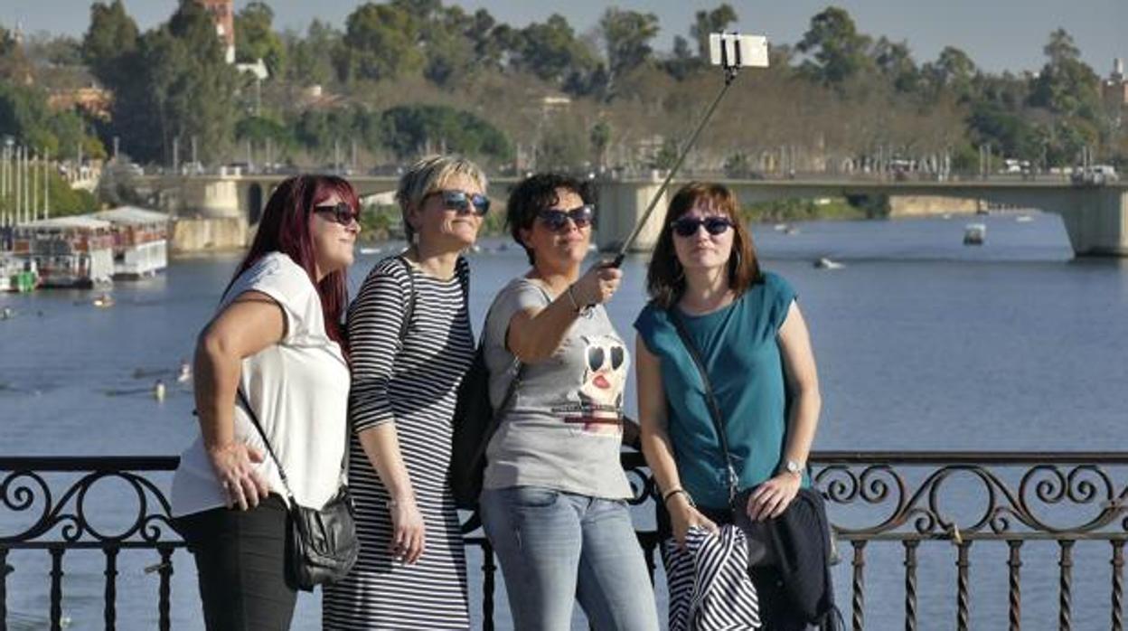 Unas turistas se fotografían en Sevilla con el río Guadalquivir de fondo