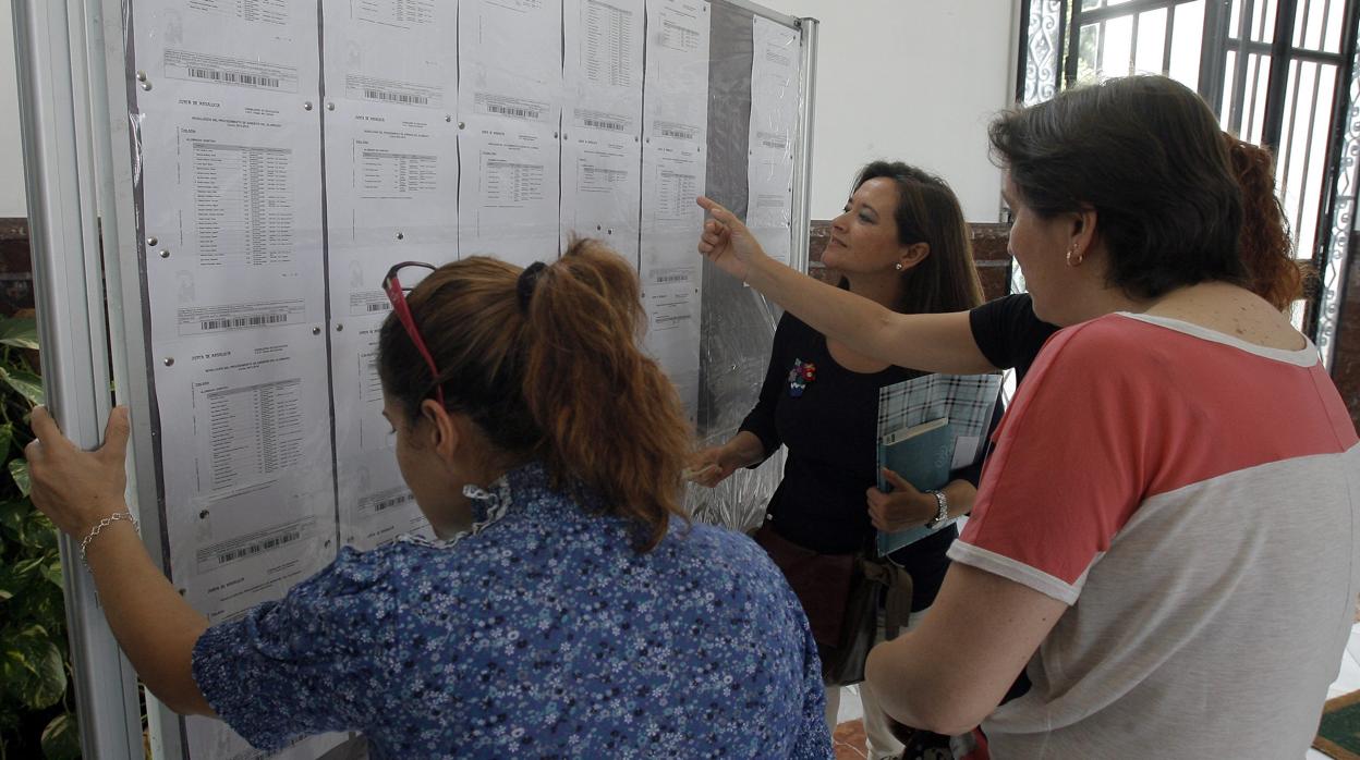 Varias personas consultan las litas de admisión de un colegio