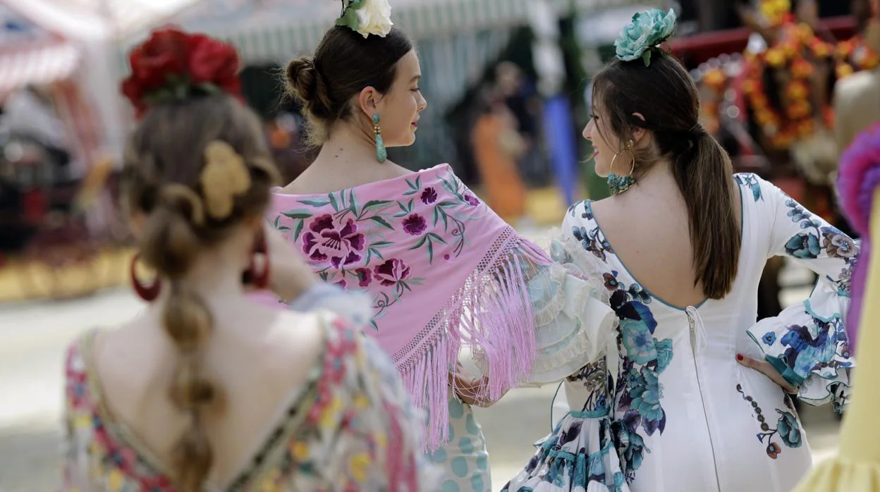 Unas jóvenes vestidas de flamenca pasean por el real