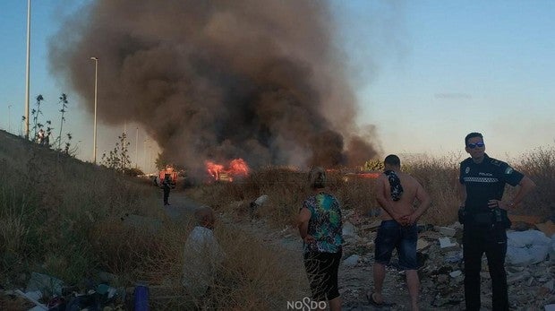 Los bomberos trabajan en la extinción del incendio cercano a la barriada de Palmete