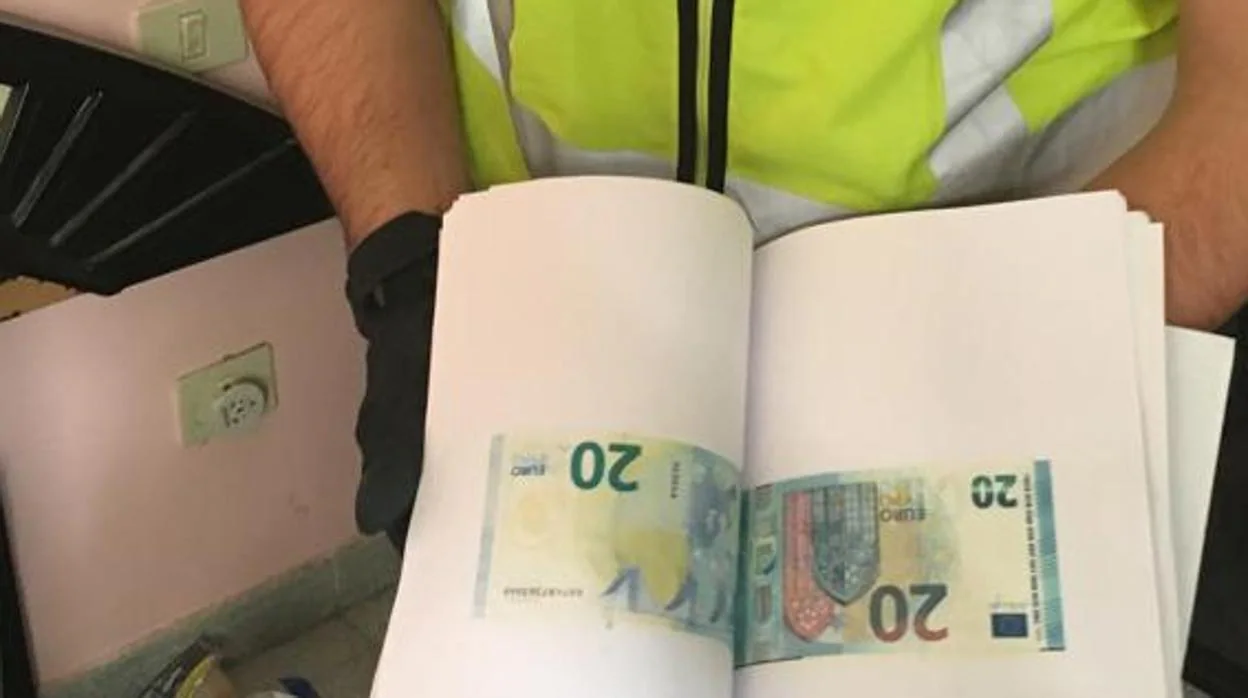 Imagen de archivo de un agente de Policía mostrando pliegos de moneda falsificada