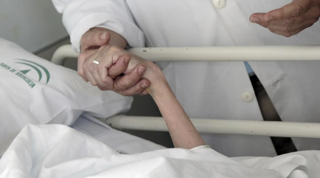 El doctor Salvador Alegre agarra la mano a Esperanza, paciente de Paliativos