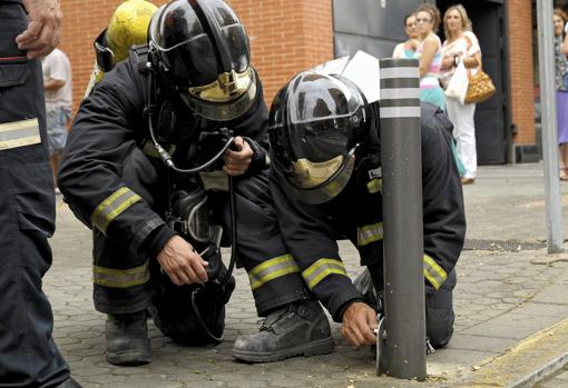 Dos bomberos levantan un pivote para que pase uno de sus vehículos