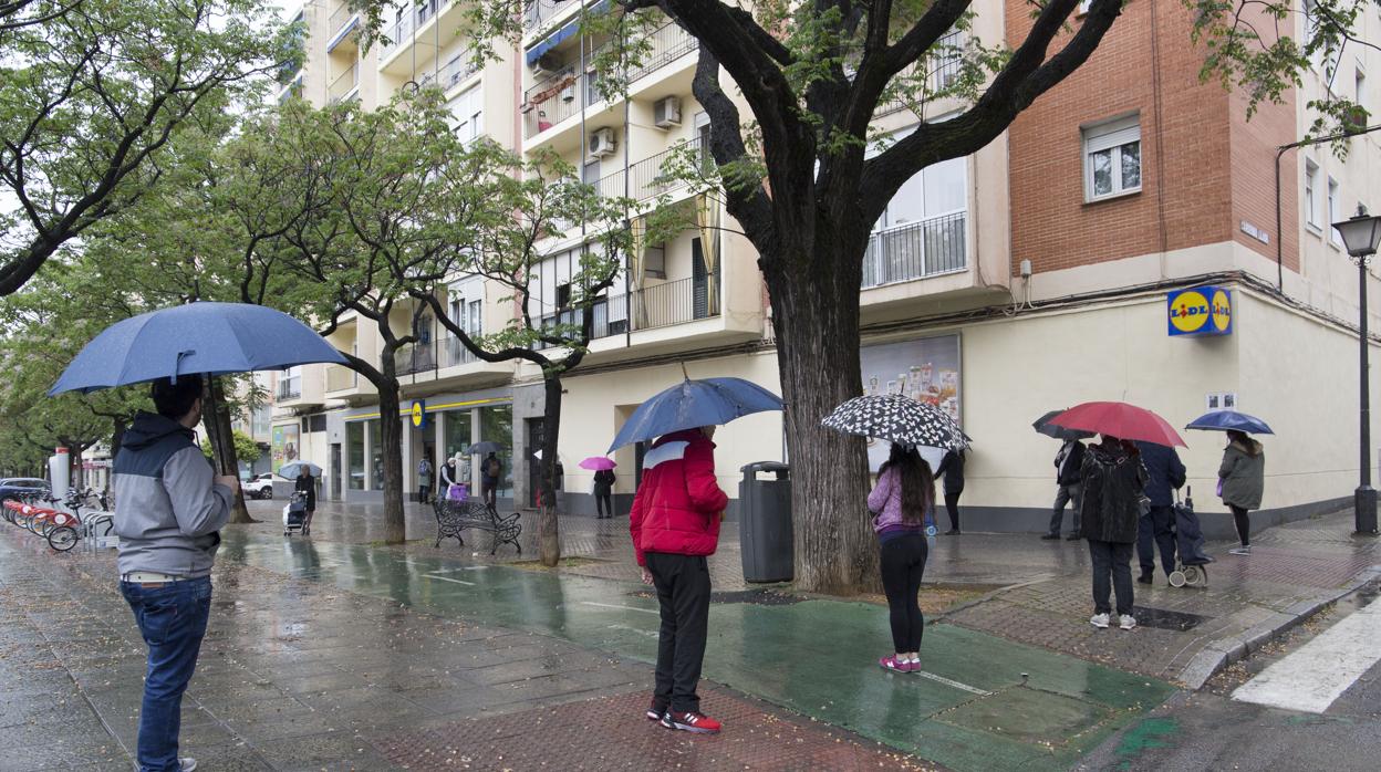 Varias personas aguardan en cola para acceder a un supermercado, este sábado en Sevilla