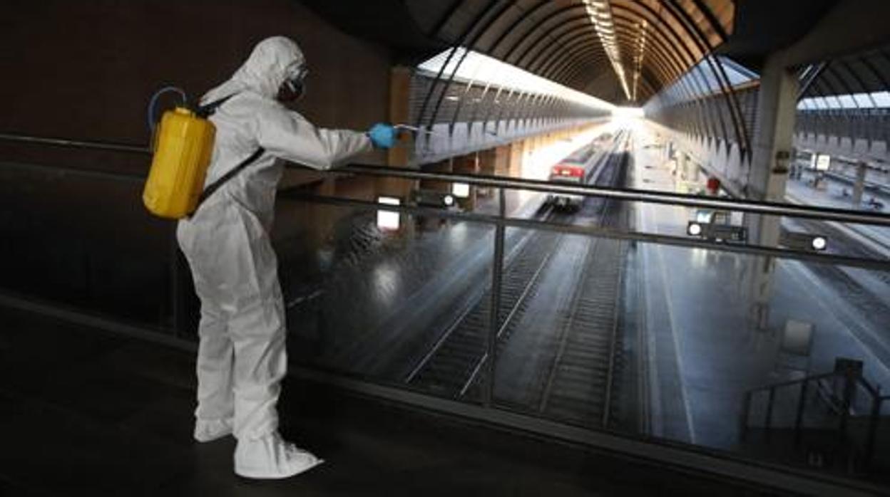 Un miembro de la UME desinfecta la estación de Santa Justa al inicio del estado de alarma