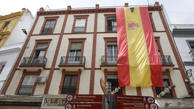 Cuelgan una gran bandera de España con crespón negro en un edificio de la plaza del Salvador