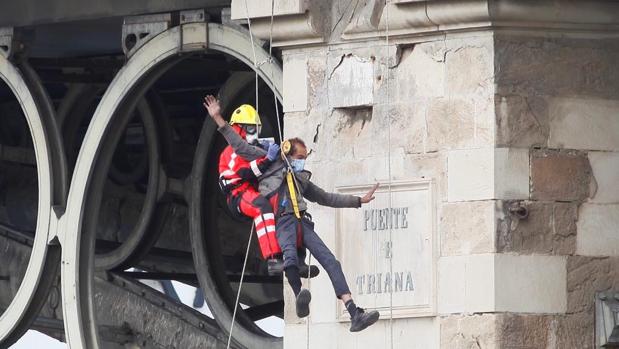 Los bomberos intervienen para rescatar a un varón del puente de Triana