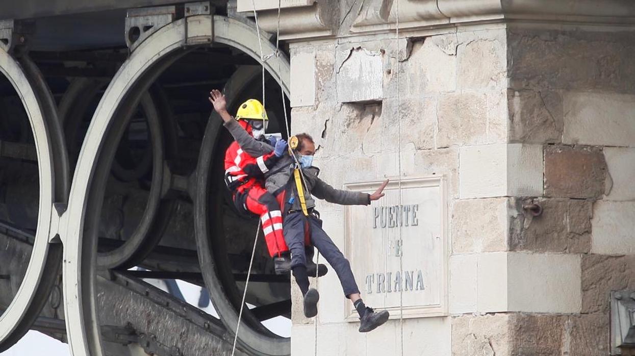 Un efectivo de Bomberos desciende al varón que se había colgado en el puente de Triana