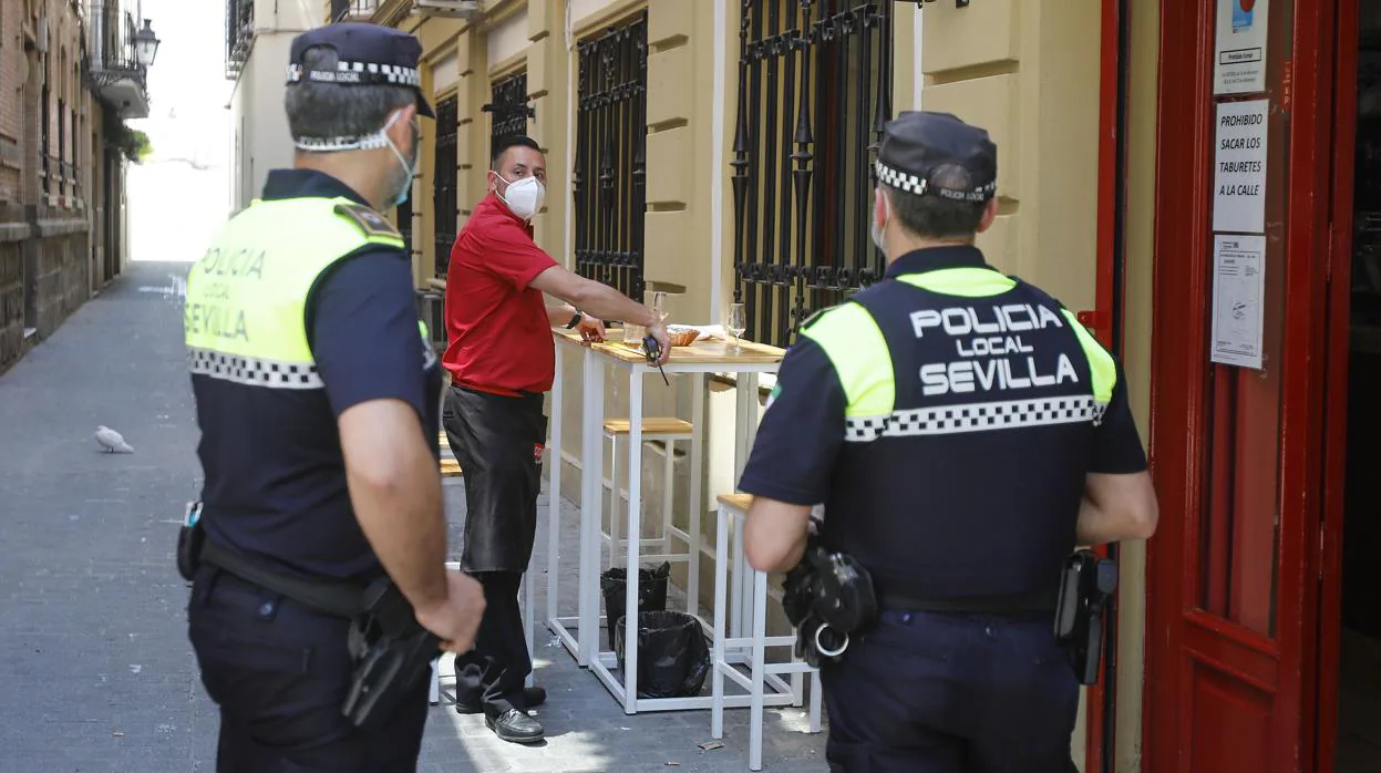 Dos agentes de la Policía Local inspeccionan un bar de Sevilla